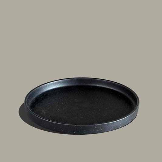 A round black tray with a textured matte finish and a raised rim