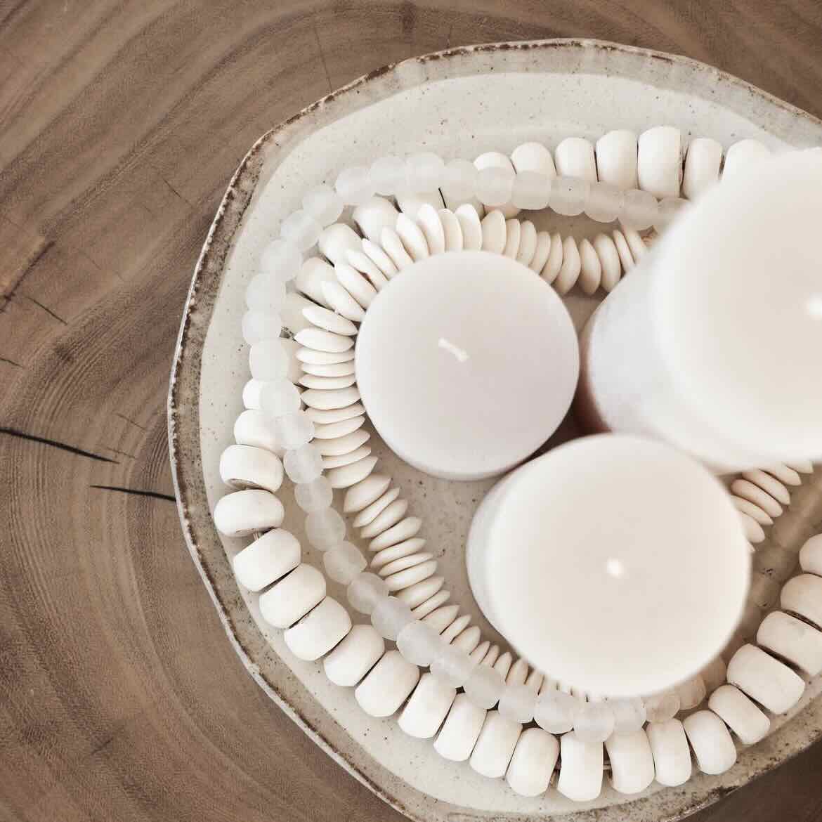 White ceramic bowl with pillar candles on a wooden surface