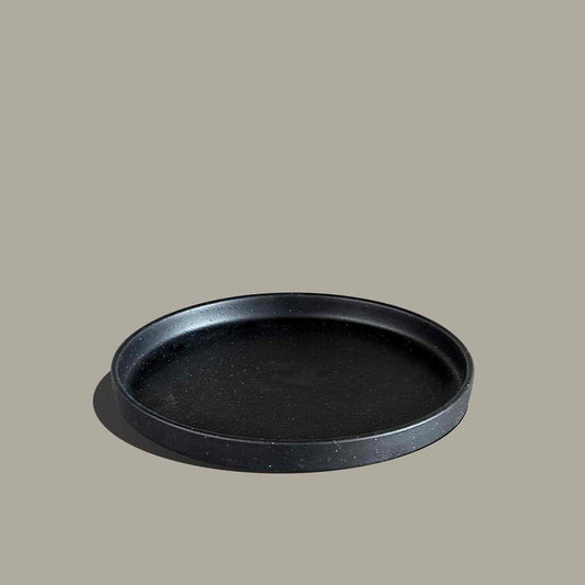 A round black tray with a textured matte finish and a raised rim