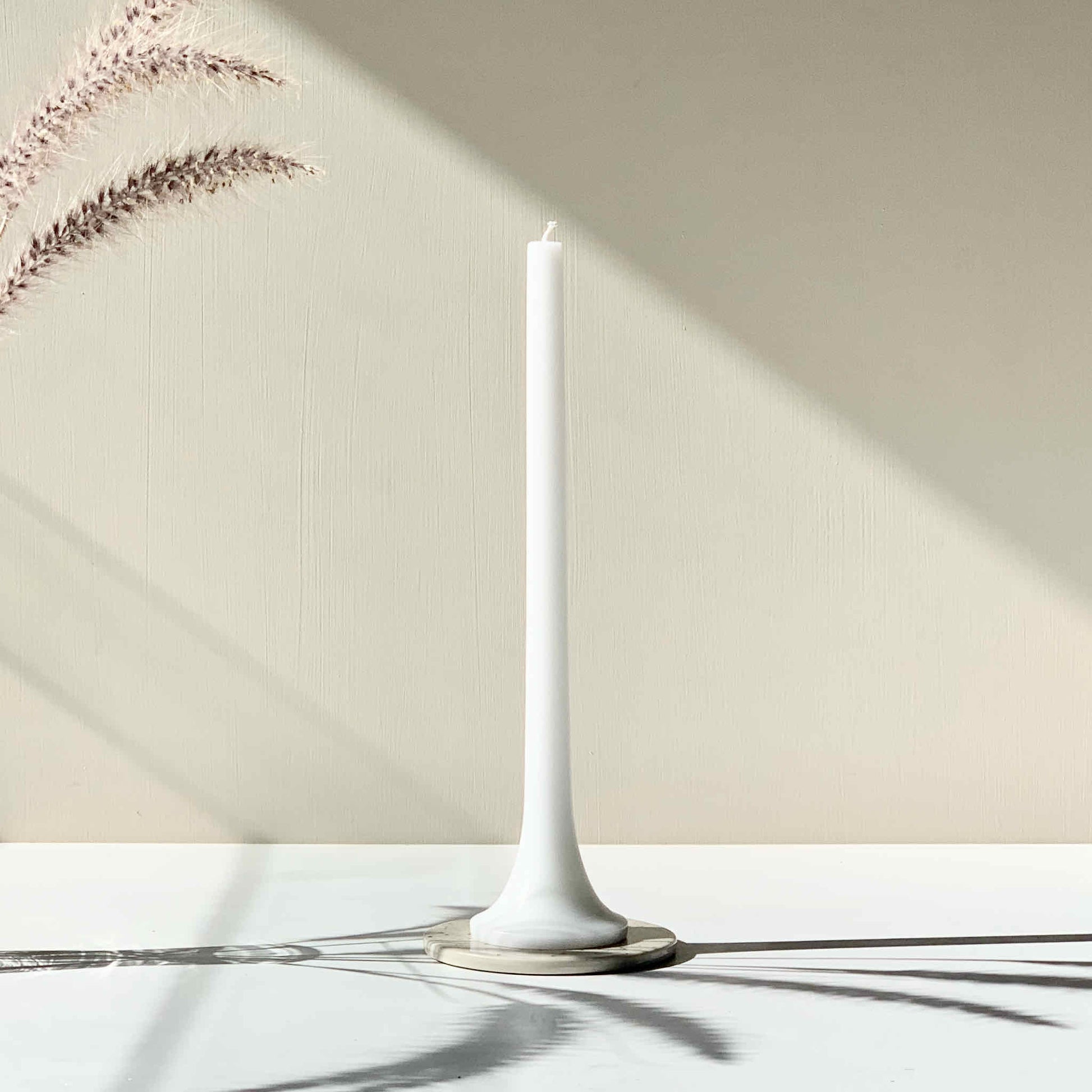 White taper candle on ceramic tray